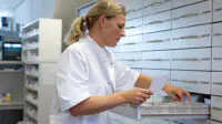 A pharmacist examines the a shelf of medicines