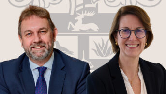 Paul and Karen together against a light brown background with the royal college of pharmacy logo between them