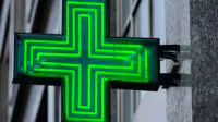 A neon green cross outside of community pharmacy