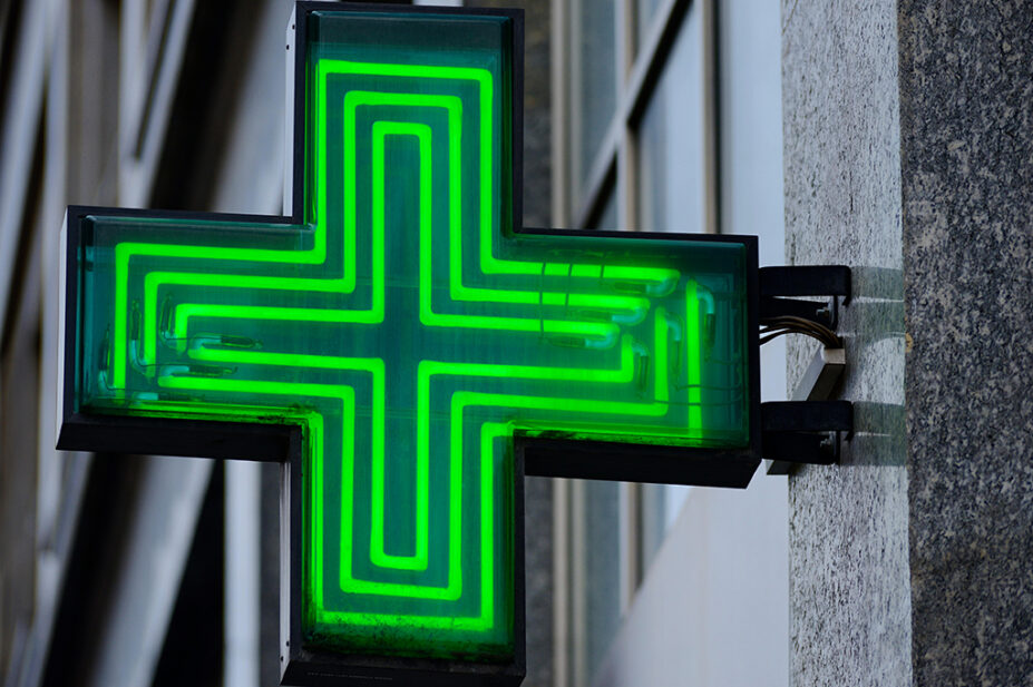 A neon green cross outside of community pharmacy