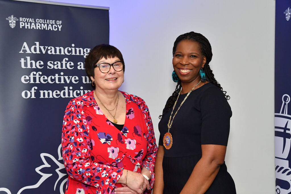 Claire and Tase stand in front of RCPharm navy banners