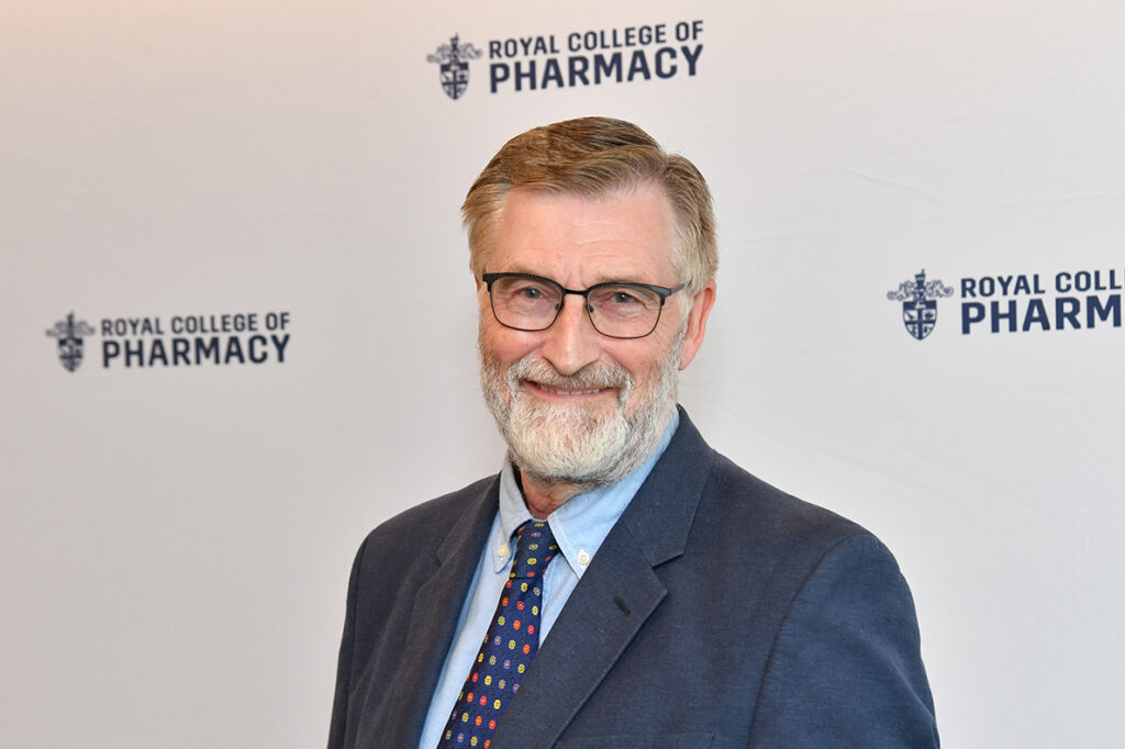 Joe stands in front of a white banner with RCPharm logos on it