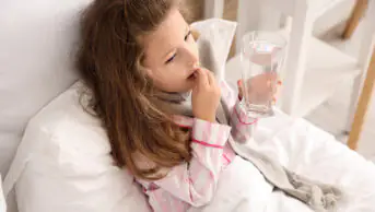 A child takes a tablet with glass of water