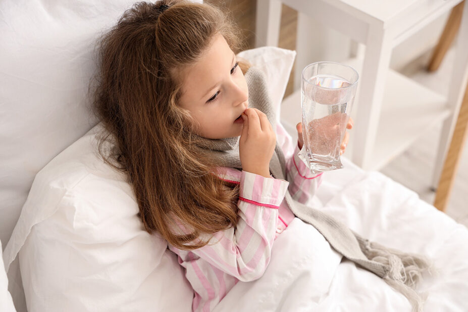 A child takes a tablet with glass of water