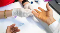 Pharmacist taking a patient's sample using finger prick test