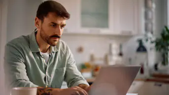 Mid adult man typing an email on laptop while working at home
