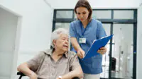 Nurse talks to older woman as she is discharged from hospital