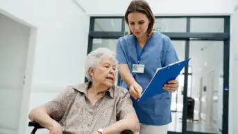 Nurse talks to older woman as she is discharged from hospital