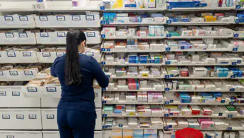 Interior view of a pharmacy with a staff dispensing medicine