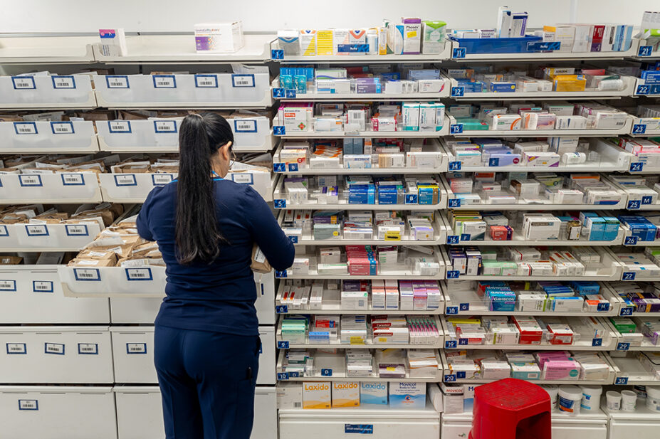 Interior view of a pharmacy with a staff dispensing medicine