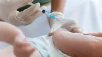A baby receives a vaccination from a healthcare professional