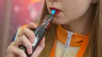 A woman smokes a vape