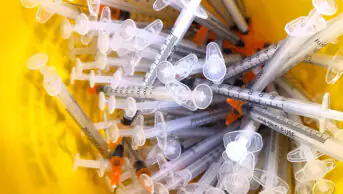 Close up of the used vaccine needles in a sharp bin