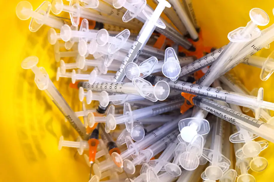 Close up of the used vaccine needles in a sharp bin