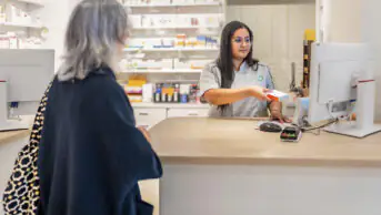 A community pharmacist scans medication at the checkout counter