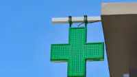 The green cross sign outside of a community pharmacy