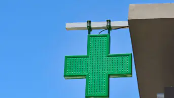The green cross sign outside of a community pharmacy