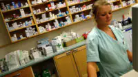 A pharmacist works on a computer in a community pharmacy