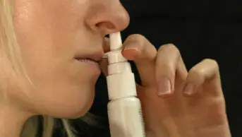 A woman uses a nasal decongestant spray