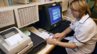 A pharmacist uses a computer in a community pharmacy