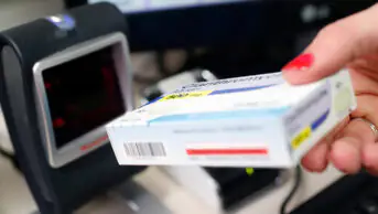 A pharmacist scans a box of medication at the till