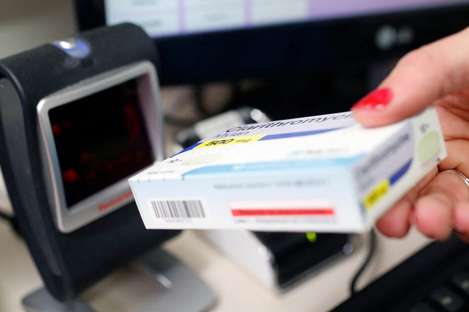 A pharmacist scans a box of medication at the till