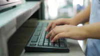 Hands typing on keyboard at pharmacy counter