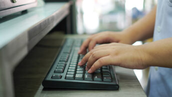 Hands typing on keyboard at pharmacy counter