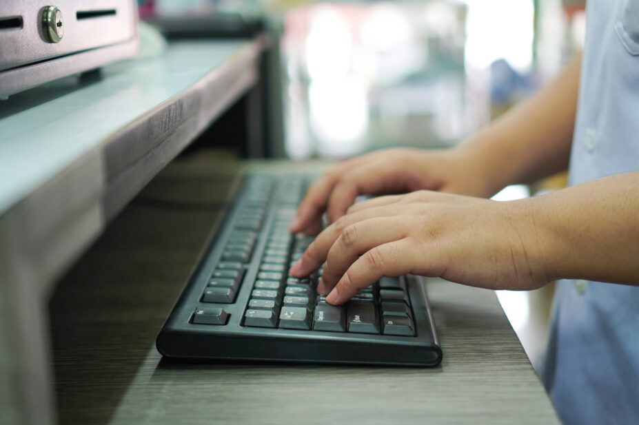 Hands typing on keyboard at pharmacy counter