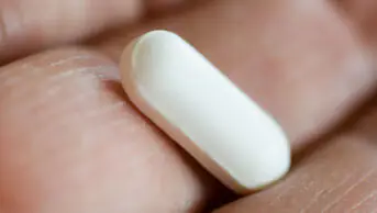 A man holds a pill in his hand