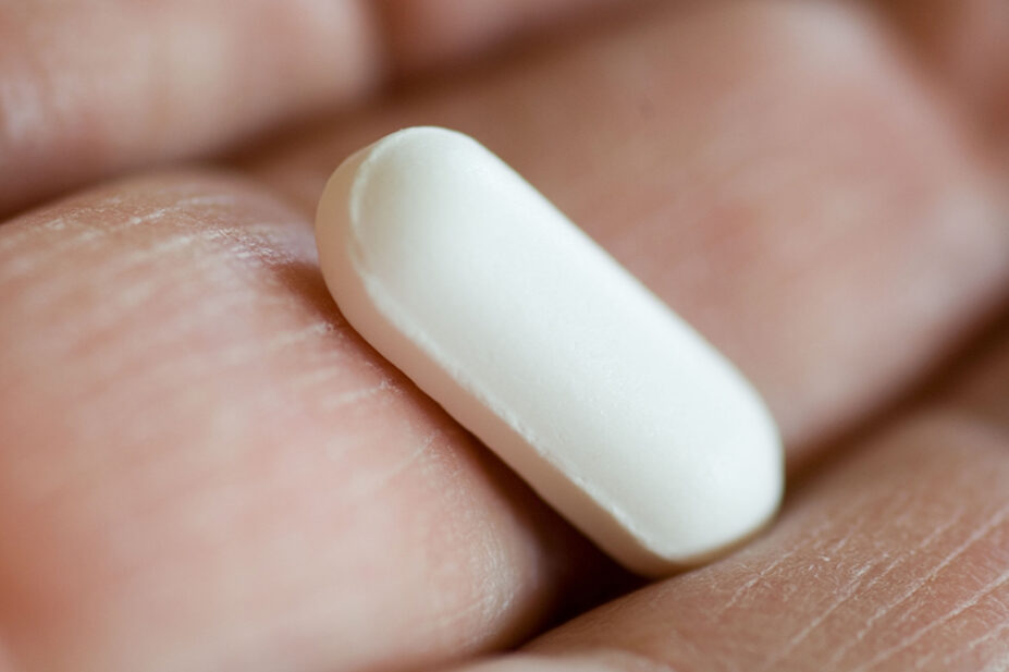 A man holds a pill in his hand