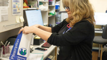 A pharmacist fills a prescription in a community pharmacy