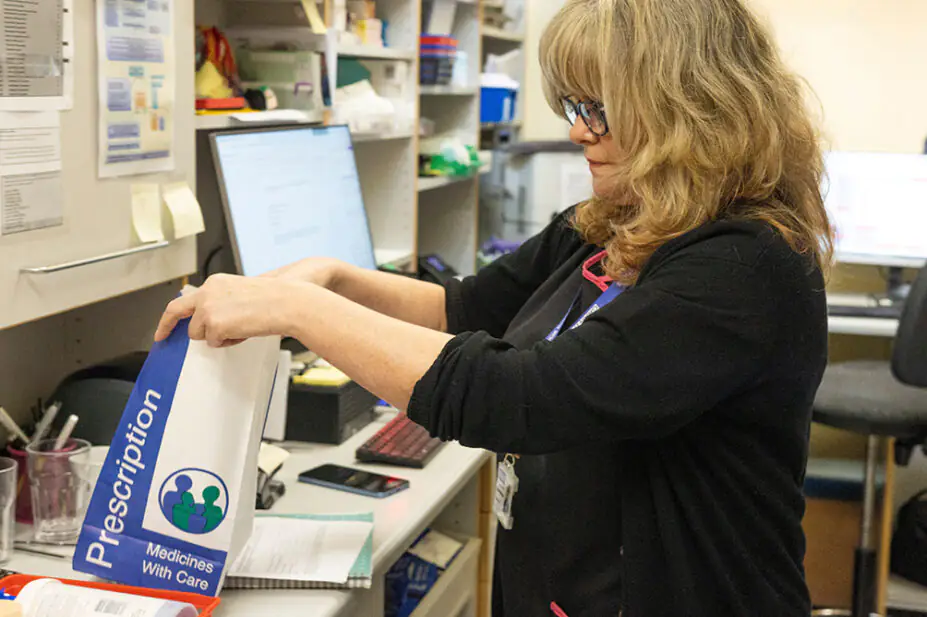 A pharmacist fills a prescription in a community pharmacy