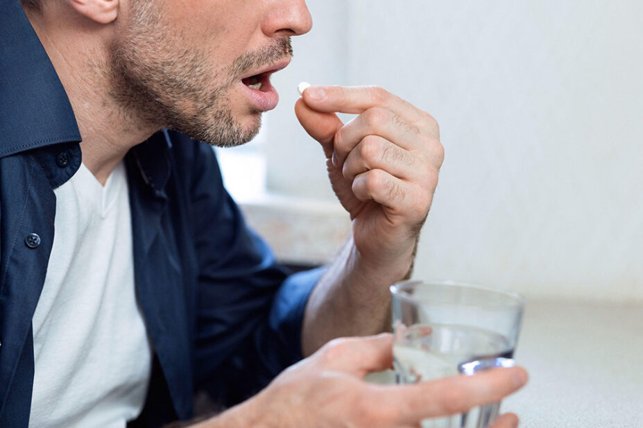 A man takes a pill with water