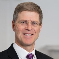 Antony Avery smiles wearing suit and tie