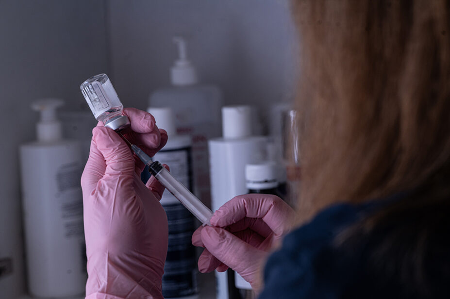 Healthcare professional preparing a syringe of medicine