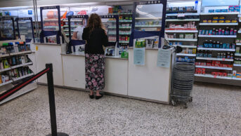 A woman at a pharmacy counter in UK pharmacy store