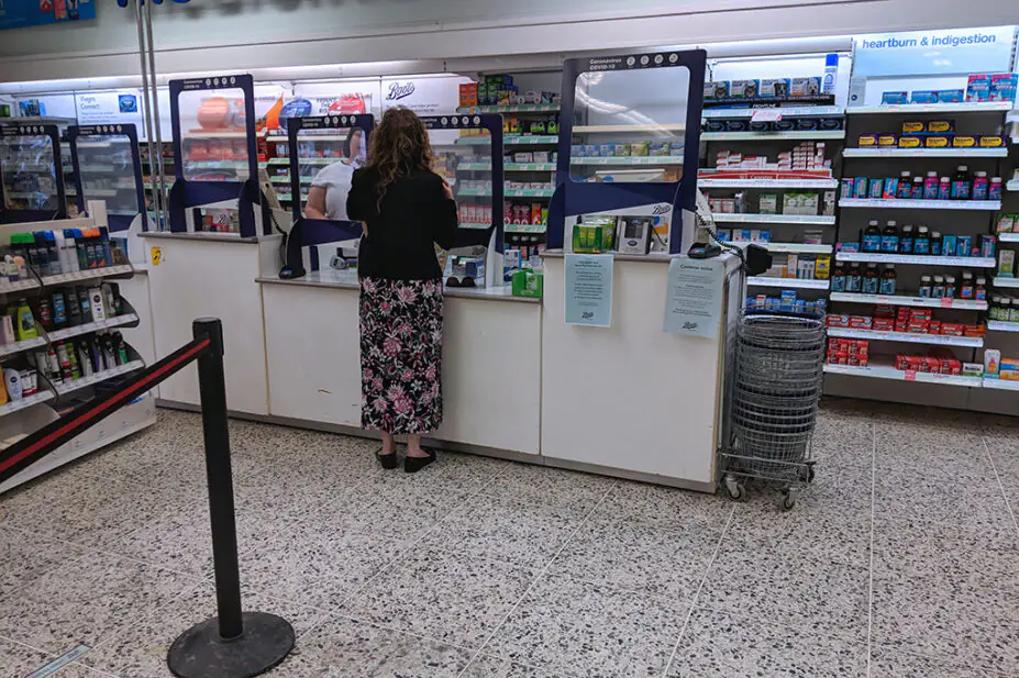A woman at a pharmacy counter in UK pharmacy store
