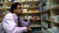 A pharmacist looks at a shelf of medicines