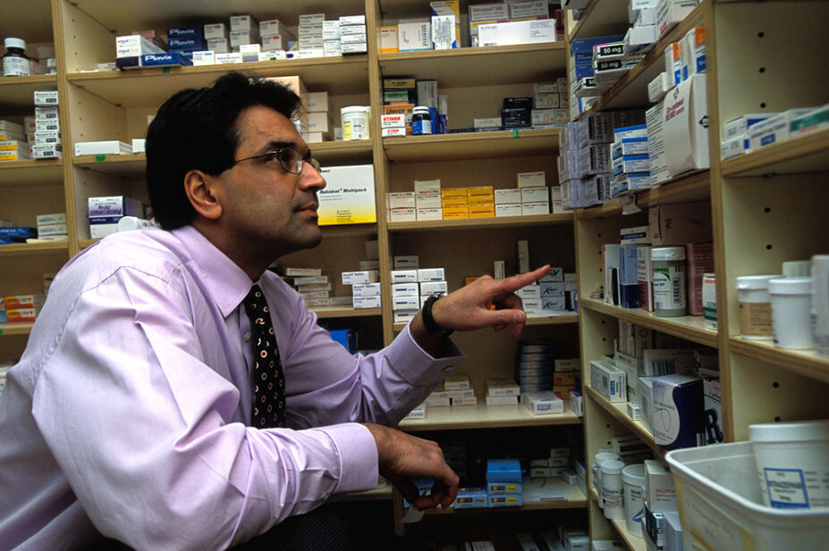 A pharmacist looks at a shelf of medicines