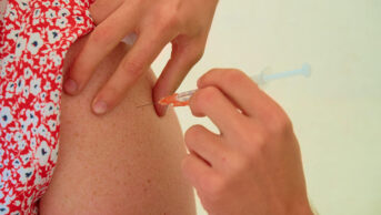 A woman receives a vaccination in her arm