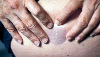 A woman places a menopausal hormone therapy patch on her stomach