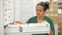 Young pharmacist at a hospital opens a prescription drawer