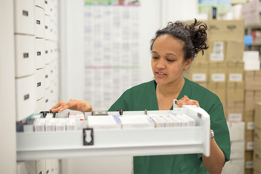 Young pharmacist at a hospital opens a prescription drawer