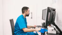 A healthcare professional checks patient records on a computer