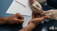 Physician taking blood sugar test