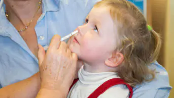 2 year old child, with her mum / mother, receives dose of Fluenz flu vaccine nasal spray immunisation from NHS Practice nurse UK