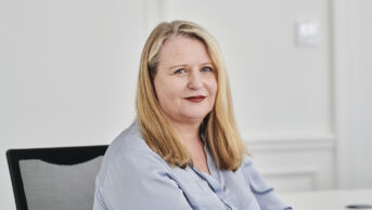 Janet Morrison sat at a desk wearing blue shirt