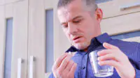 A man takes a tablet with water
