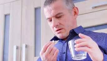 A man takes a tablet with water